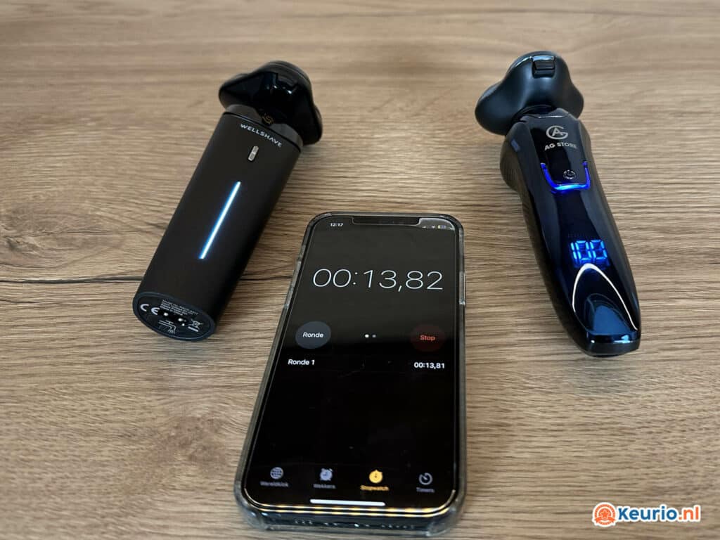 Een smartphone met een stopwatch van 13,82 seconden, geflankeerd door twee elektrische scheerapparaten op een houten oppervlak.